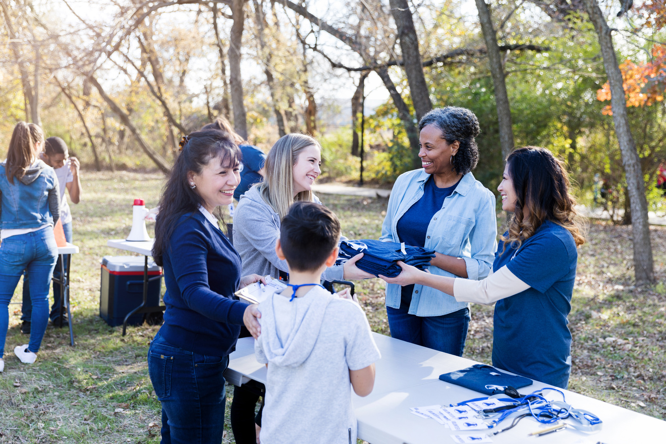 Community event coordinators hand out t-shirts to volunteers